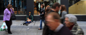 ALMERIA, SPAIN - APRIL 04:  People pass by a homeless man sitting with his pet dog outside a fashion store on April 4, 2009 in the coastal town of Almeria, southeast Spain. Before the real estate bubble burst, Almeria and it's province where booming. During the recent downturn in Spain's economy, regions which are heavily dependent on residential construction and real estate have seen unemployment levels soar. The province of Almeria currently has one of Spain's highest unemployment rates at almost 25 per cent against a nationwide figure of around 13.9 percent.  (Photo by Jasper Juinen/Getty Images)